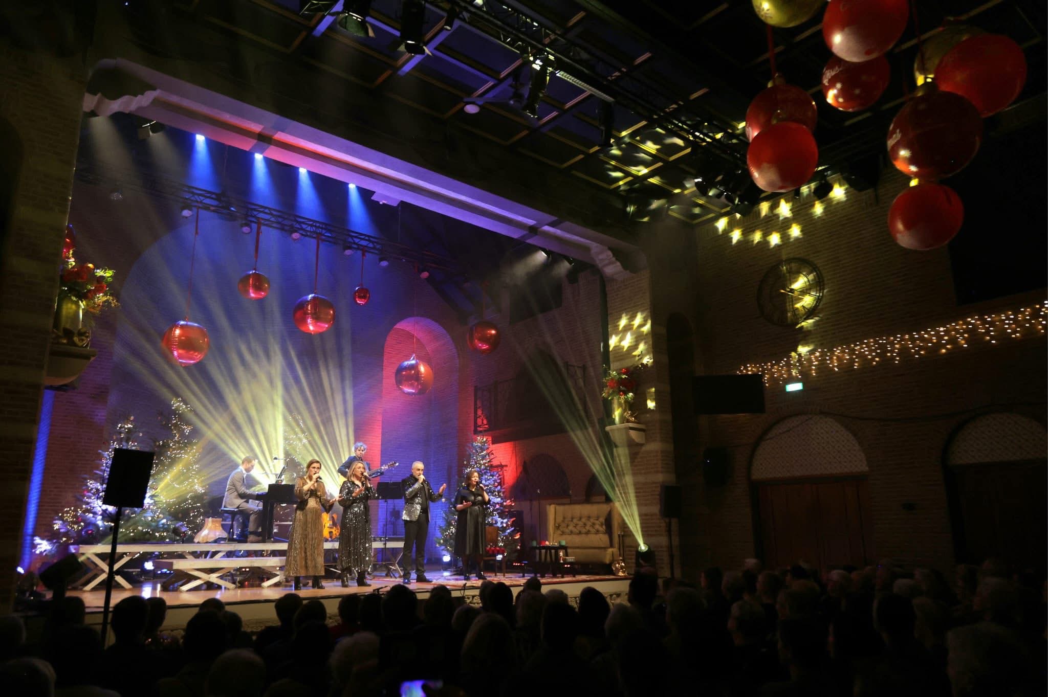 Zangers en muzikanten op het verlichte podium van Duvelshof, met publiek vooraan