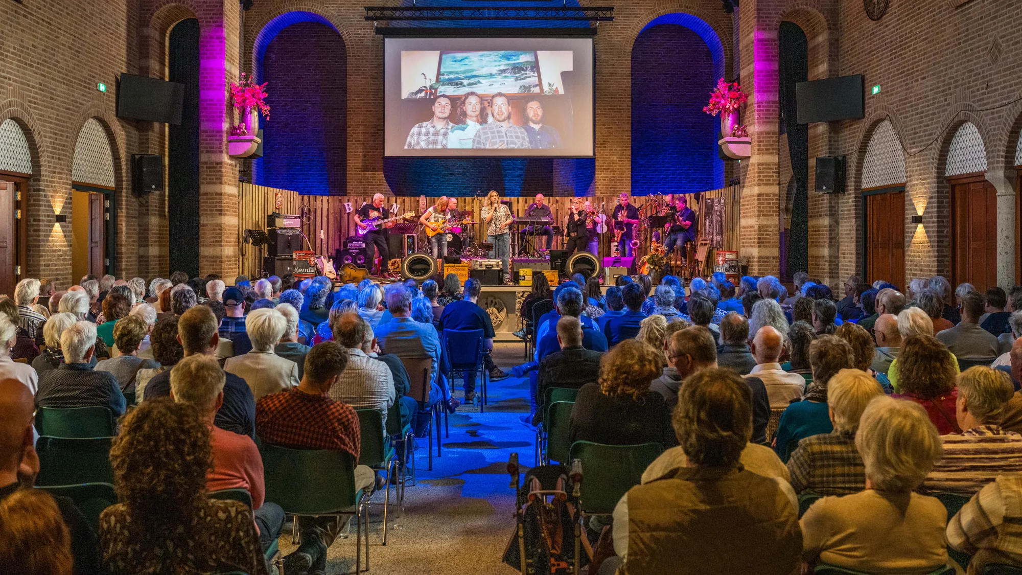 De zaal van Duvelshof tijdens de laatste editie van Blues in the Barn, met publiek voor het podium en verlichte bakstenen bogen